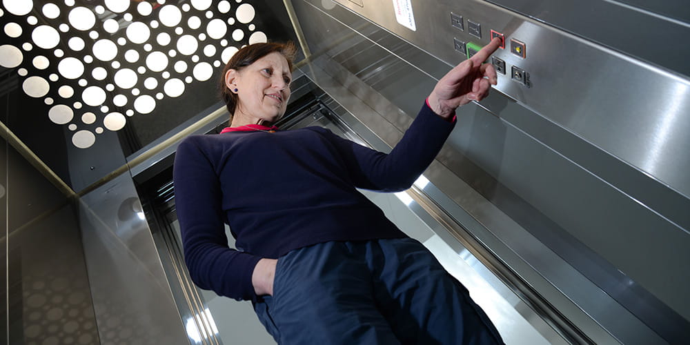 Woman in passenger lift using control panel buttons