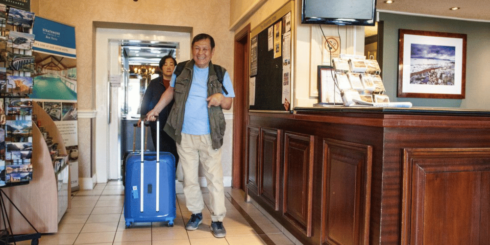 Man existing a Hotel passenger lift with his suitcase